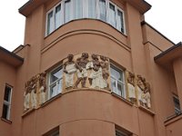 Trg bana Jelačića 4, trokatna stambeno-poslovna palača Popović na uglu sa Splavnicom sagrađena je 1907. Detalji pročelja  Visoki zaobljeni ugao s velikom zastakljenom plohom dodatno je istaknut balkonskim rešetkama od kovanog željeza i reljefnim figuralnim frizom izvedenim u poznatoj zagrebačkoj tvornici keramike Josipa Kalline po predlošku Ivana Meštrovića. Baranyaijevu plodnu suradnju s umjetnicima, koja se u najrazličitijim iskazima očituje tijekom cijeloga mu opusa, ovdje sjajno ilustrira stan i atelijer u kojem se neposredno po povratku iz Beča u Zagreb nastanio Tomislav Krizman, slikar i grafičar koji je u ovoj sredini značajan i kao pokretač umjetničkih zbivanja i začetnik modernog dizajna, a ta je »bohemska mansarda« gotovo puna tri desetljeća funkcionirala kao njihov “genius loci”.